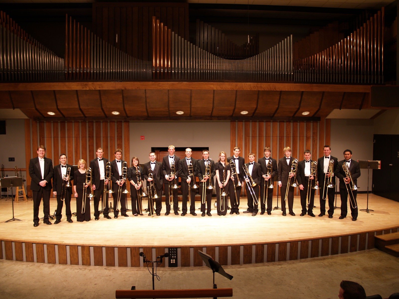The BYU trombone choir on stage after a recital, trombones in hand